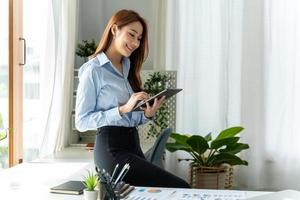 creatieve aziatische jonge vrouw die aan tablet in haar studio werkt. foto