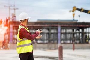 ingenieur landmeter met behulp van walkie-talkie op bouwplaats foto