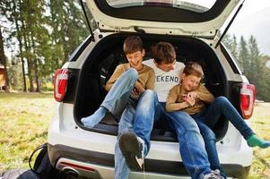 familie bij voertuiginterieur. vader met zijn zonen. kinderen in de kofferbak. reizen met de auto in de bergen, sfeerconcept. foto