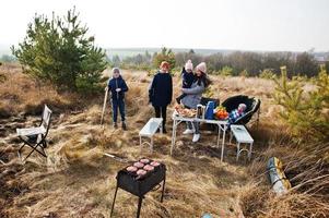 familie barbecueën op een terras in het dennenbos. bbq-dag met grill. foto