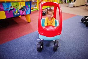 schattige babymeisje rijdt op een plastic auto in indoor speelcentrum. foto