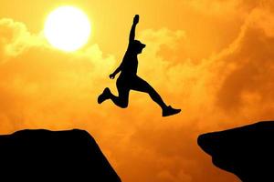 silhouet van een atleet die op een rotsachtige klif springt foto