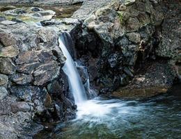 stromende waterval over rotsen naar een kleine pnd foto