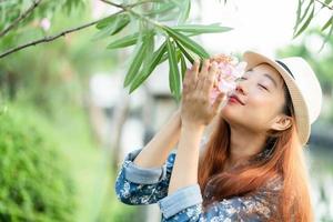 mode meisje buiten portret, mooi meisje met lang haar in het park de geur van bloemen foto