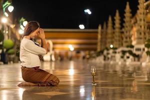 jonge aziatische vrouw die traditionele kleding van thailand draagt om respect te betuigen aan het boeddhabeeld in wat suthat thepwararam foto