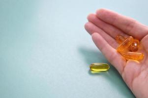 gele omega 3 capsules liggend in de palm van de hand op een groene achtergrond. vrije ruimte voor tekst. goede voeding, gezondheidszorg. bioadditieven, vitamines, aminozuren, visolie. medicijnen, medicijnen. foto