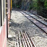 speelgoedtrein die zich op berghellingen beweegt, prachtig uitzicht, een zijberg, een zijvallei die zich op een spoorlijn naar de heuvel beweegt, tussen groen natuurlijk bos. speelgoedtrein van kalka naar shimla in india foto