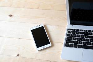 laptop en smartphone op een houten tafel. foto
