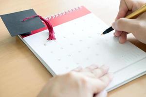 hand met pen en markering op kalender foto