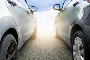 samenvatting van naast van twee auto's op de asfaltweg. parkeer de auto buiten naast elkaar. of bereid je voor op de race. met achtergrond buiten van blauwe lucht en witte wolken met zonlicht. foto