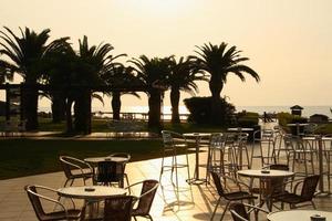 een leegstaand hotel aan zee. straat café op de achtergrond van palmbomen bij dageraad. foto