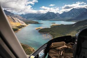 binnenkant van helikopter die op rotsachtige bergen vliegt met turkoois meer en blauwe lucht foto