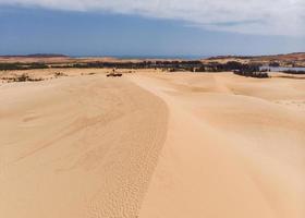 luchtfoto van bruine kronkelende zandduinen met vierwielige auto foto