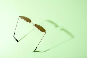 minimalistische afbeelding van zonnebril met schaduw op groene achtergrond. foto