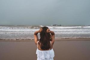 jonge vrouw die zich eenzaam en verdrietig voelt terwijl ze naar de zee kijkt op een sombere dag foto