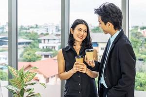 lekkere koffiepauze, zakenvrouw die een espresso drinkt tijdens een praatje met een jonge collega terwijl ze op kantoor staat foto