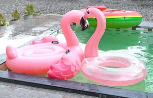 kleurrijke zwembadvlotter, roze ring drijvend op het zwembad, zwembad rubberen ring flamingo foto