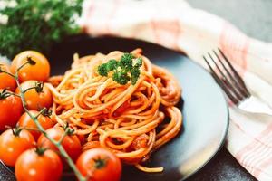 spaghetti italiaanse pasta geserveerd op zwarte plaat met tomaat en peterselie in het restaurant italiaans eten en menu concept - spaghetti bolognese foto