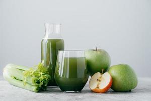 horizontaal schot van vers gemengde appels en cerely voor uw gezonde voeding. vegetarische groene drank in glazen. detox drank, fruit en groente rond foto