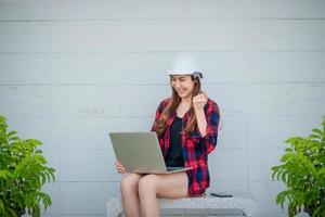 een aziatische vrouw kijkt naar het nieuws op een laptop en ze vertoont tekenen van vreugde. foto