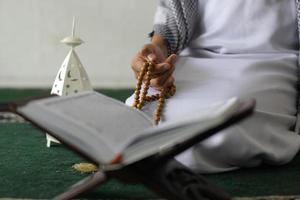 mannenhand met moslim rozenkralen, gebedskralen met koran, op witte achtergrond foto