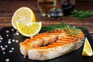 gegrilde zalm vis op stenen bord. Salt atlantic zalm gebakken op grill met citroen foto