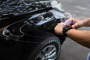 man die een slim horloge gebruikt, controleert de bandenspanning naar zijn slimme auto met draadloze verbinding, toekomstig technologieconcept foto