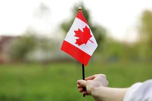 vlag van canada, nationaal symbool zwaaien tegen, zonnige dag. Canadese vlag in de hand van de vrouw. selectieve focus foto