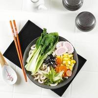 udon, japanse noedels met verschillende groenten topping in keramische kom. foto