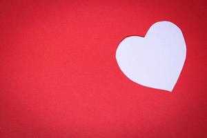 wit hartvormig papier op een rode achtergrond met het concept valentijnsdag foto