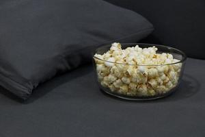 glazen beker met gezouten popcorn in een grijze fauteuil. foto