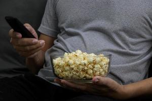 glazen beker met gezouten popcorn in een grijze fauteuil. foto