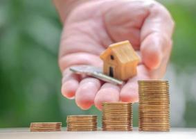 huis- of thuismodel op een stapel munten met home-sleutel. concept voor lening, vastgoedladder, financieel, hypotheek, vastgoedinvestering, belastingen en bonus. foto