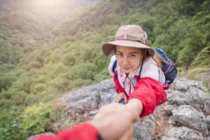 helpende hand. wandelaar vrouw die hulp krijgt bij het wandelen glimlachend gelukkig overwinnend obstakel. toeristische backpackers lopen op de berg, jong koppel reizen. foto