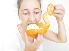 negenenveertig jaar oude vrouw in een wit t-shirt tegen een witte achtergrond met een sinaasappel foto