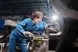 professionele jonge blanke vrouwelijke industrie-ingenieurswerknemer werkt in veiligheidsuniform met precisiegereedschappen voor metaalbewerking, mechanische draaimachines en werkplaats voor reserveonderdelen in de staalfabriek. foto