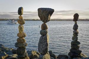 de kunst van het balanceren van rotsen met water, wolken en lucht op de achtergrond foto