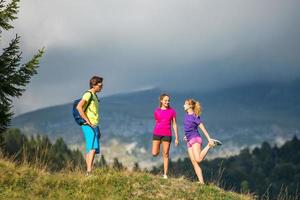 atletische trainer in de natuur strekt zich uit tot twee meisjes foto