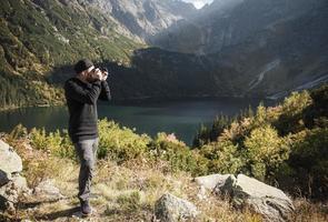 jonge man fotograaf fotograferen met digitale camera in een bergen. foto