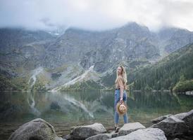 jonge vrouw die op meer in bos reist. foto