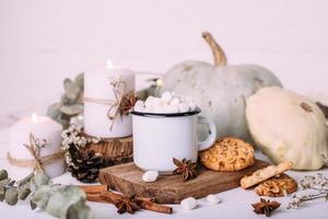 herfstcompositie met cacao met marshmallows, koekjes, pompoen en kaarsen foto