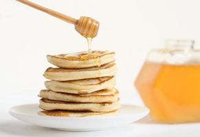 zelfgemaakte pannenkoeken in een stapel en gietende honing, goedemorgen, familieontbijt. vers geoogste boerenhoning. foto