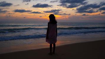 silhouet van babymeisje staande op het strand op zoek naar de zonsondergang of zonsopgang aan de zee verbazingwekkende lichte natuur landschap-achtergrond. foto