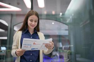 jonge zakenvrouw op het werk en het lezen van papier op kantoor foto