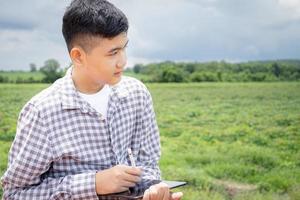 plattelandsjongen die tablet gebruikt om gegevens bij te houden over het werken op landbouwgebieden foto