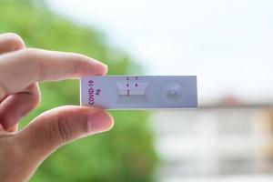 man met snelle antigeentestkit met negatief resultaat tijdens uitstrijkje covid-19 testen. coronavirus zelf-neus- of thuistest, lockdown en thuisisolatieconcept foto