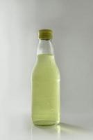 glazen fles met geel water op witte achtergrond foto