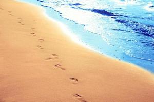 wandelen op het strand, voetstappen achterlatend in het zand. foto