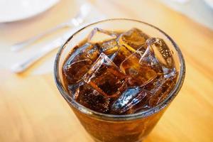 cola glas frisdrank met ijs op houten tafel op restaurant achtergrond foto