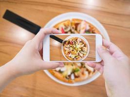 vrouw die foto van pizza neemt met mobiele smartphone